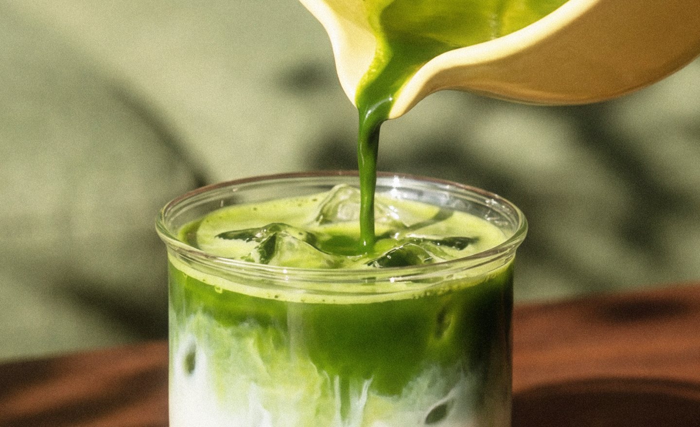Matcha being poured over an iced latte